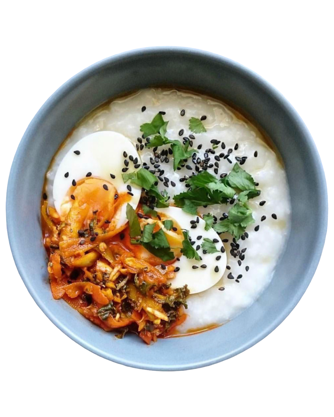 Bowl of oatmeal with kimchi, eggs, and garnishes on a white background
